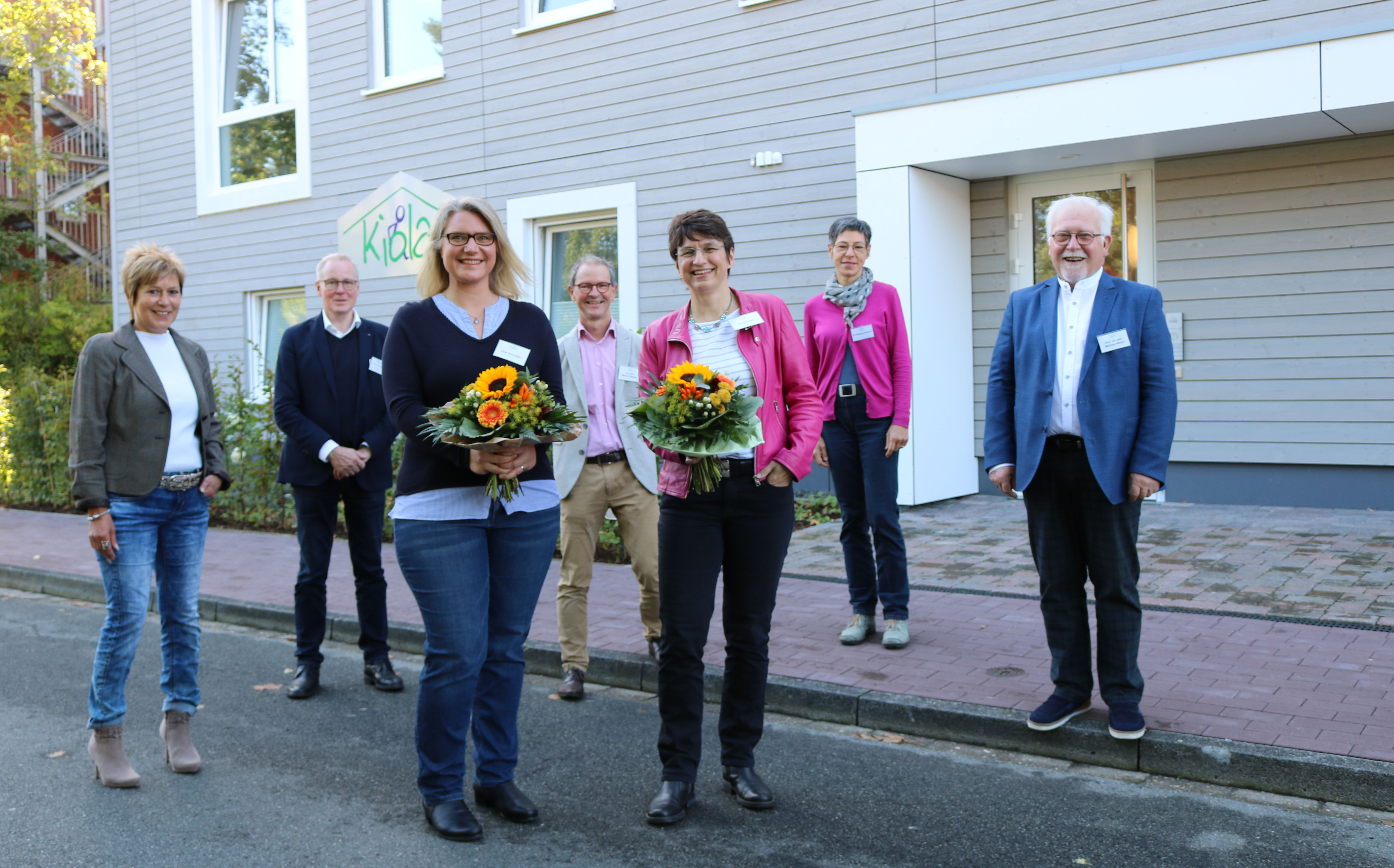 Koordinatorin ANja Schröder (1. Reihe von links) und Einrichtungsleiterin Ute Dorczok freuen sich mit Bürgermeisterin Christine Wolf (2.Reihe von links), Diakonie-VorstandThomas Feld sowie den Kiola-Vorstandsmitglieder Dr. Michael Wagner, Dr. Regina Erdmann und Prof. Dr. Michael Albani über die offizielle Eröffnungsfeier im KIOLA-Haus. Foto:Kerstin Kempermann